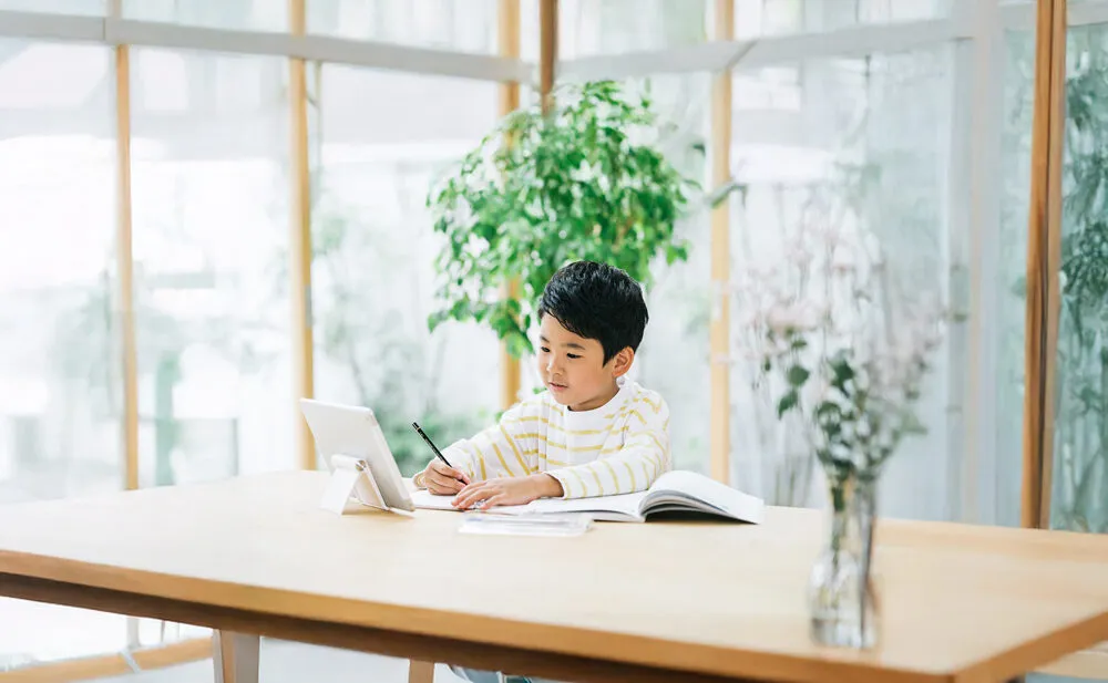 タブレット学習に集中する小学生の男の子。自宅でのオンライン学習の様子